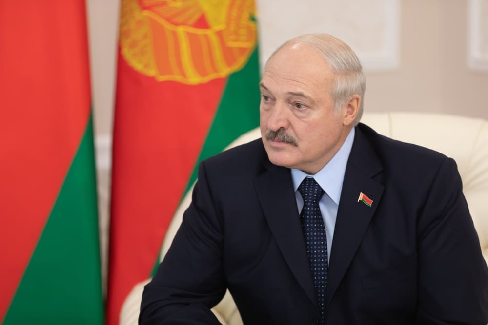 Alexander Lukashenko sits at a table with the flag of Belarus visible behind him