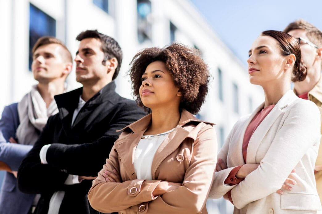 A diverse group of professionals with arms crossed, looking forward