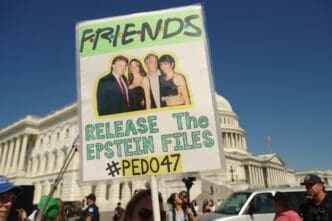 A protester holds a sign featuring a photo of three people and text demanding the release of "The Epstein Files" at the U.S. Capitol