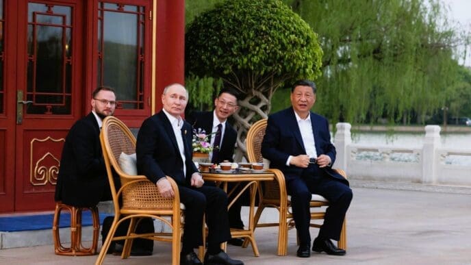 Vladimir Putin and Xi Jinping are seated with two other men at a small table outside