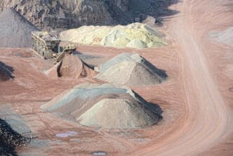 A quarry with piles of different colored aggregates and a processing plant