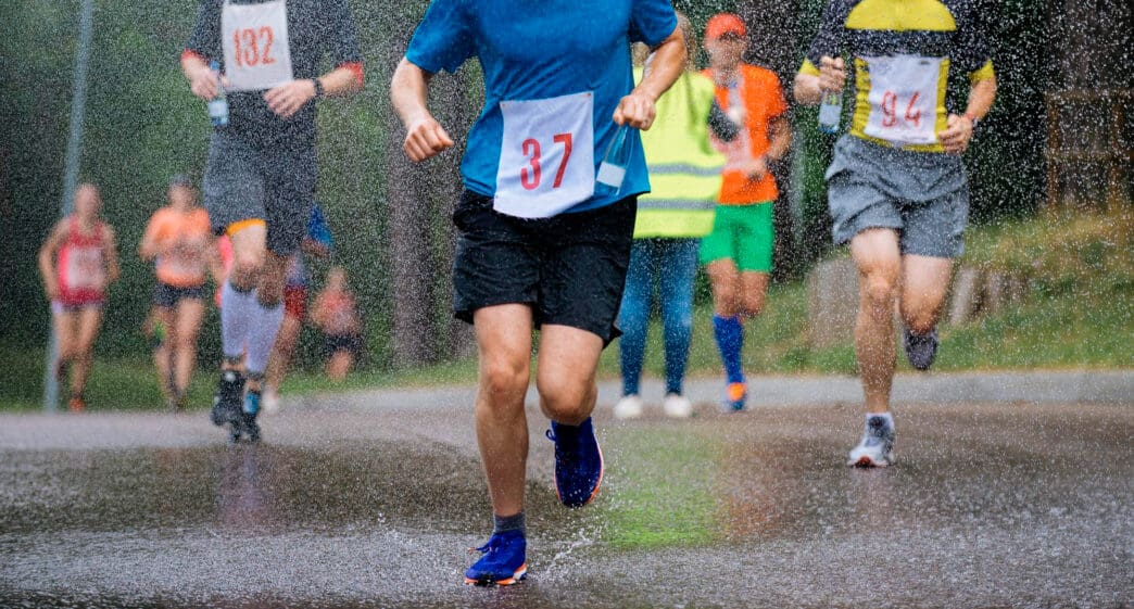 Runners splash through puddles during a multi-day race in the rain