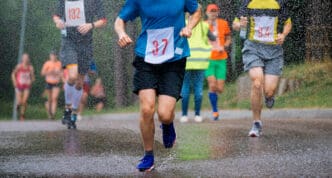 Runners splash through puddles during a multi-day race in the rain