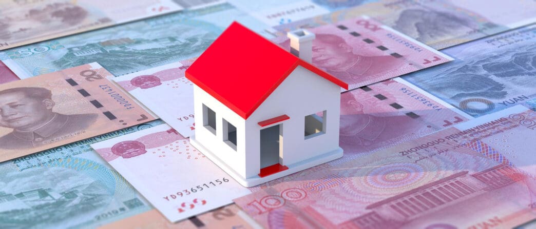 A white house with a red roof sits on Chinese currency