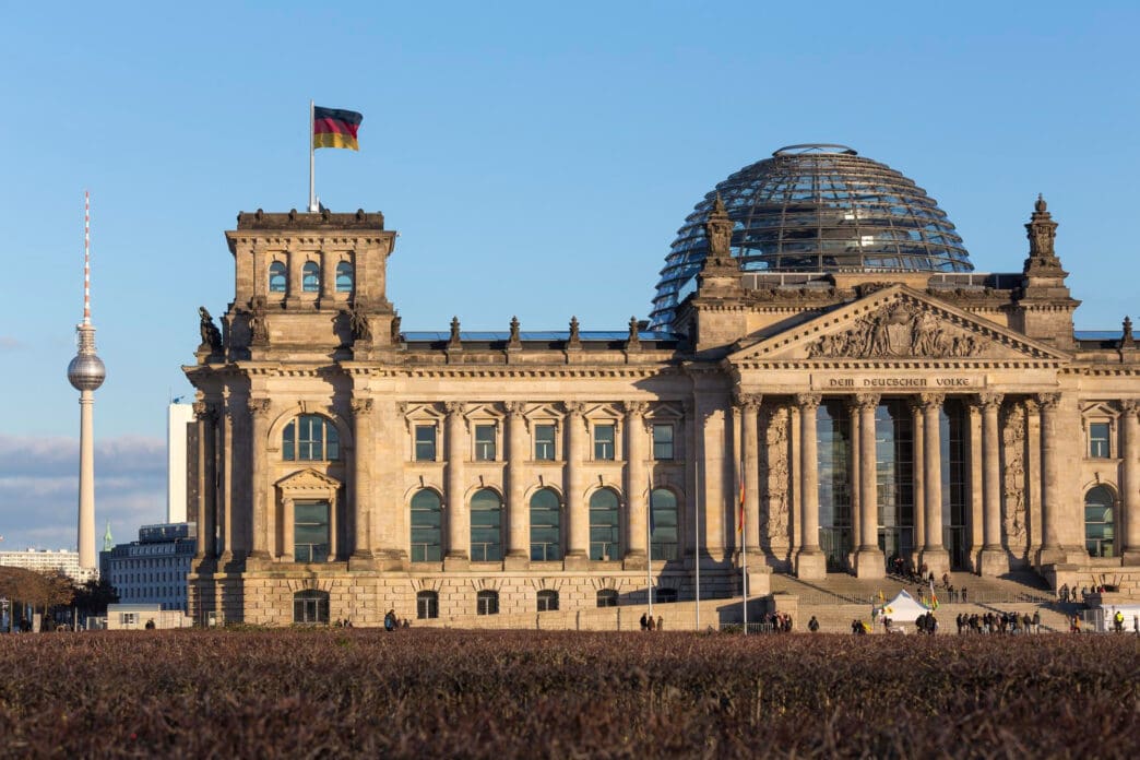 The Reichstag building in Berlin with the German flag and Fernsehturm in the background