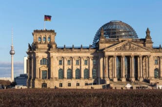 The Reichstag building in Berlin with the German flag and Fernsehturm in the background