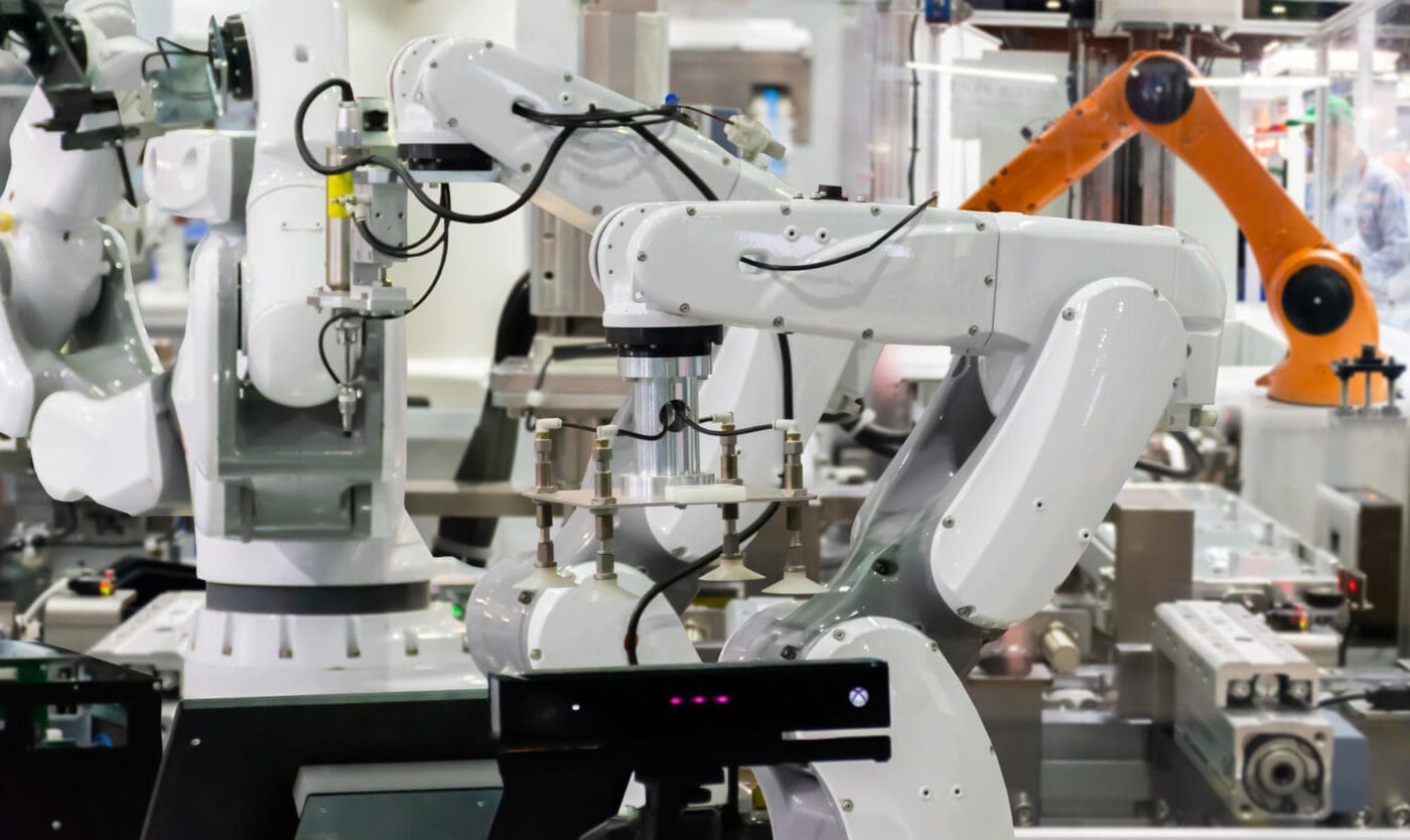Robotic arms in a factory setting with bright industrial lighting