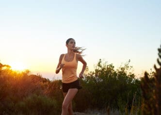 Woman running on a trail at sunset with wind blowing her hair