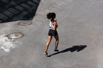 Woman with curly hair runs on pavement with manhole covers