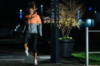 A woman in a running jacket and leggings performs a nighttime exercise on a paved path in Miami