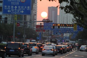 Traffic on a busy street in Shanghai at sunset with the sun low in the sky