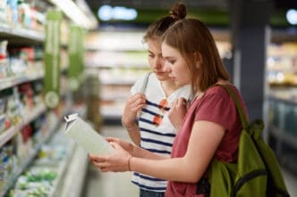 Two young women in a supermarket aisle look at a product on a shelf