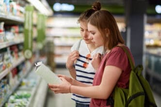 Two young women in a supermarket aisle look at a product on a shelf