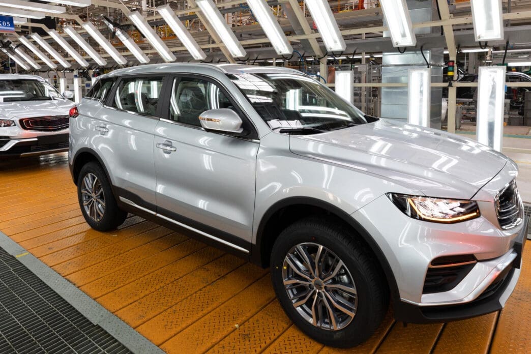 Silver Chery SUV on a yellow platform in a factory with bright lights