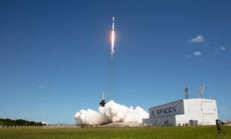 A SpaceX rocket launches into the sky, leaving a trail of smoke and fire