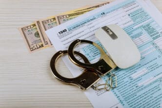 Handcuffs, computer mouse, and money on a tax form