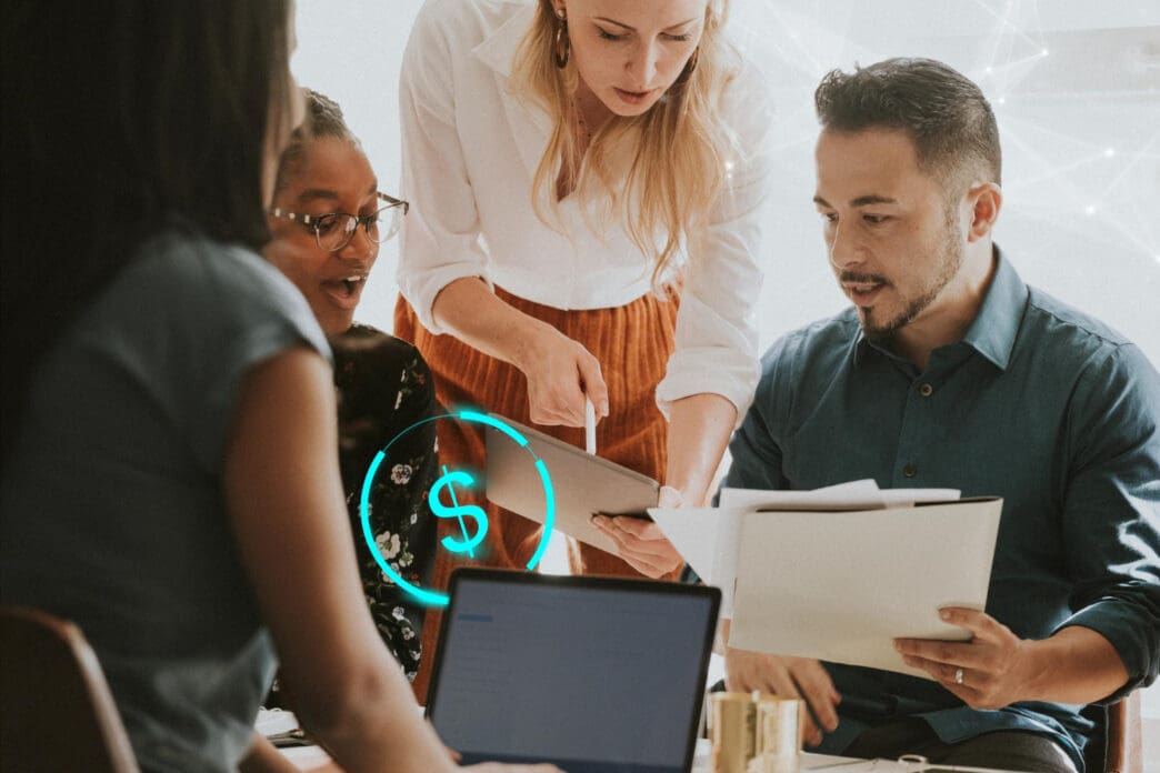 A diverse group of people in a meeting looks at a tablet and a laptop as a digital dollar sign floats in the foreground, representing tech for nonprofit donations