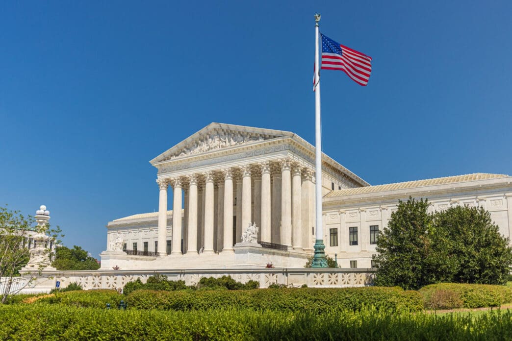 The United States Supreme Court building stands majestically with the American flag flying high in front of it