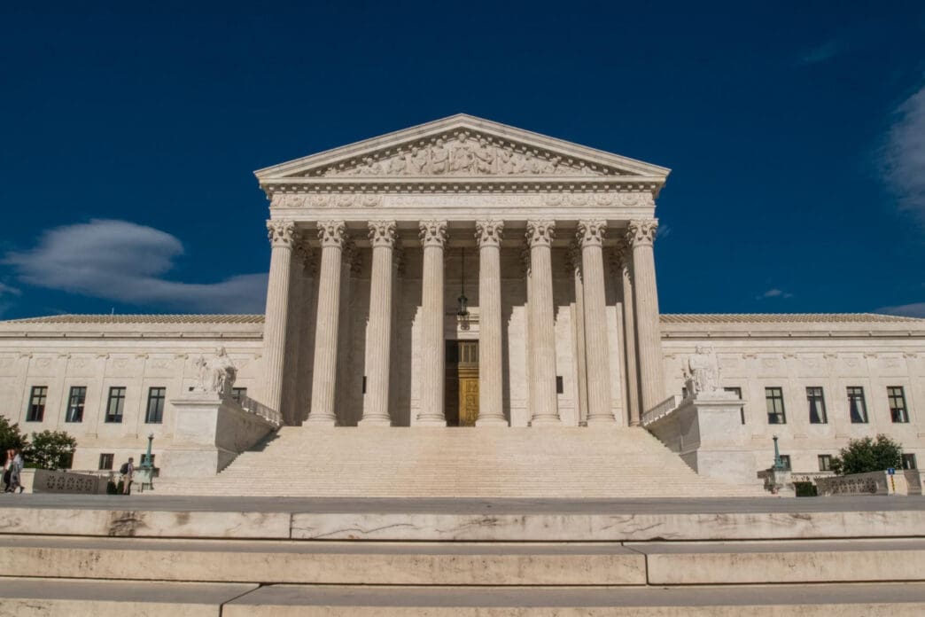 The United States Supreme Court building with its grand staircase and columns under a deep blue sky