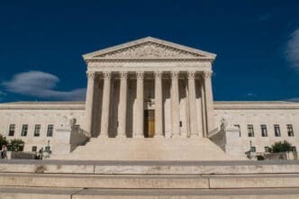 The United States Supreme Court building with its grand staircase and columns under a deep blue sky
