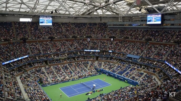 The interior of Arthur Ashe Stadium, filled with a large crowd, with the retractable roof completely closed over the tennis court