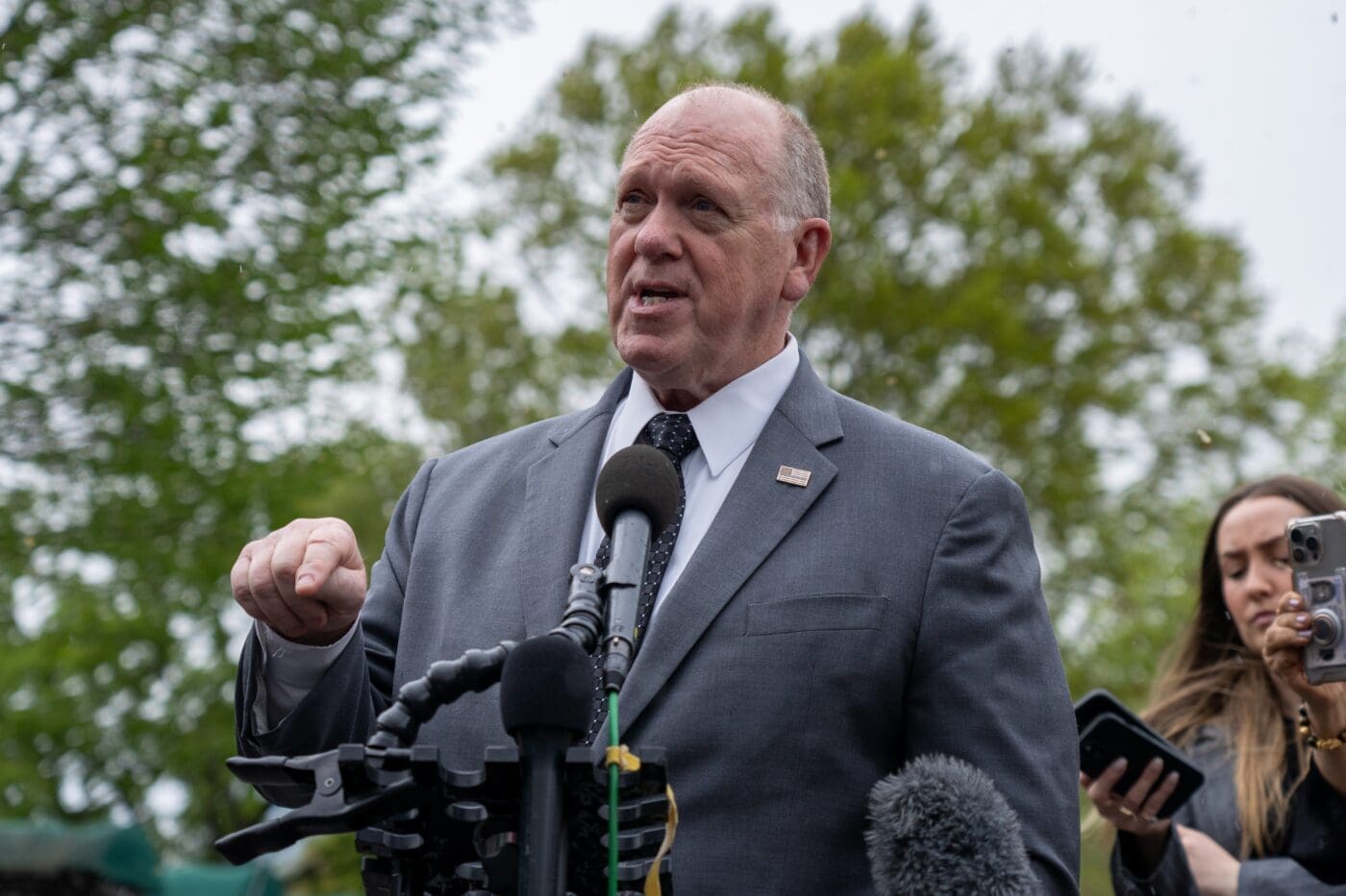 Tom Homan speaks at a press conference with a microphone in front of him