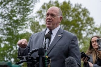 Tom Homan speaks at a press conference with a microphone in front of him