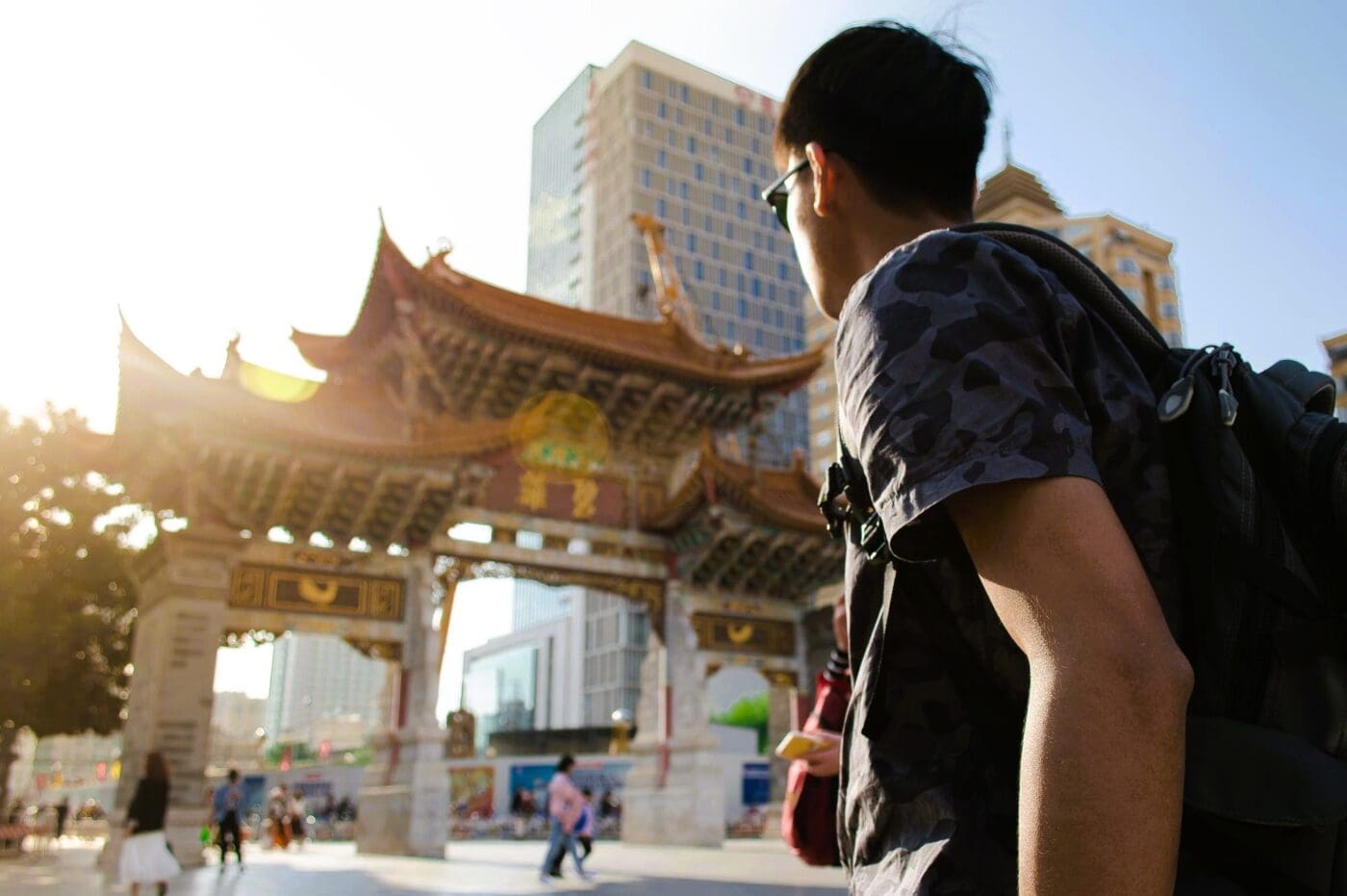 Young man with backpack looking at traditional Chinese architecture
