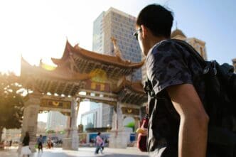 Young man with backpack looking at traditional Chinese architecture