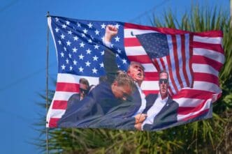 American flag with images of Donald Trump and others, waving against a blue sky