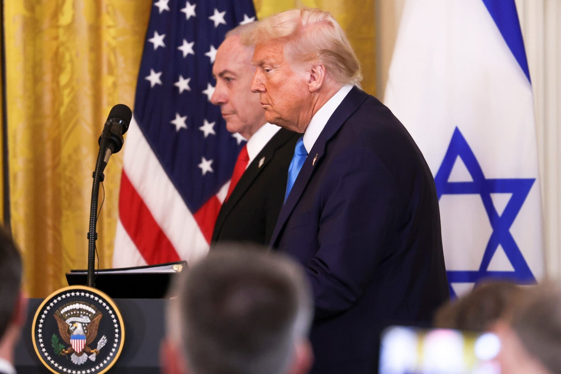 Donald Trump and Benjamin Netanyahu stand with flags behind them at a press conference.