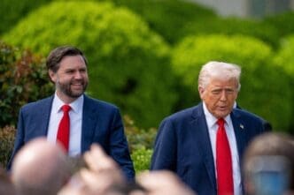 Donald Trump and JD Vance walk together, with lush greenery in the background