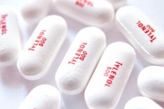 White oval pills with red "Tylenol 500" imprint scattered on a white surface