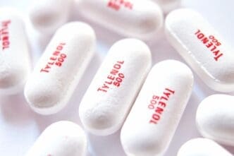 White oval pills with red "Tylenol 500" imprint scattered on a white surface