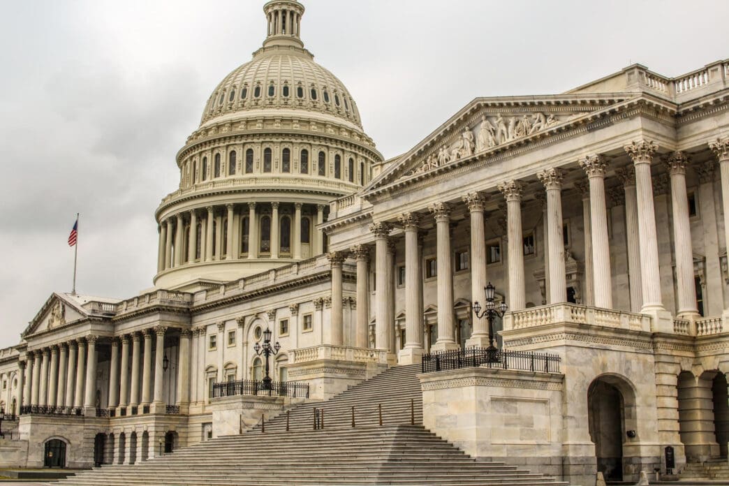 The U.S. Capitol Building with its dome and grand staircase under a cloudy sky