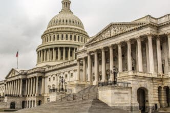 The U.S. Capitol Building with its dome and grand staircase under a cloudy sky