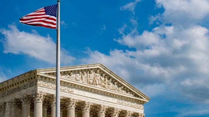 The American flag flies high on a flagpole over the facade of the U.S. Supreme Court building