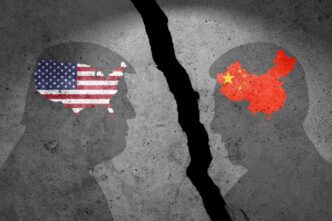 Two head silhouettes face each other across a large crack, with the US and Chinese flags inside them
