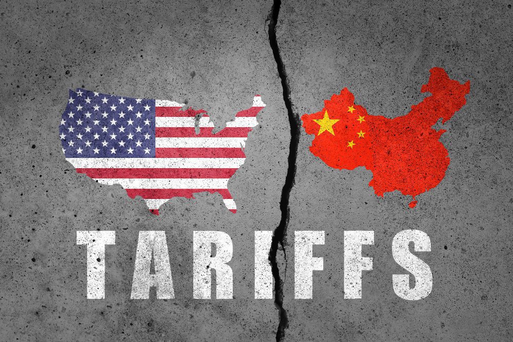 A cracked concrete wall with maps of the United States and China on opposite sides and the word "Tariffs" below