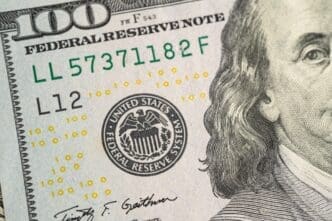 A close-up detail of a one hundred dollar bill showing the Federal Reserve seal and serial numbers