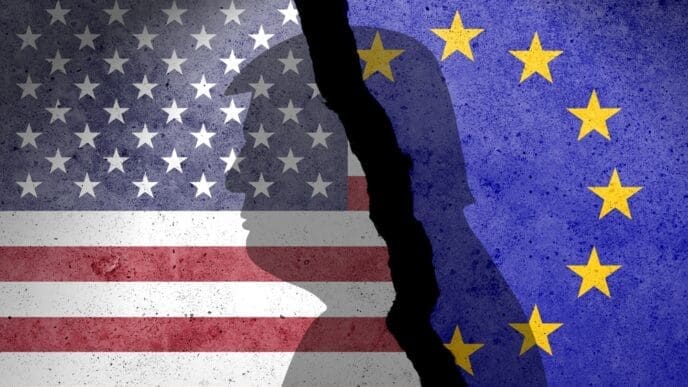 The American and European Union flags are shown on a cracked concrete wall with silhouettes of heads