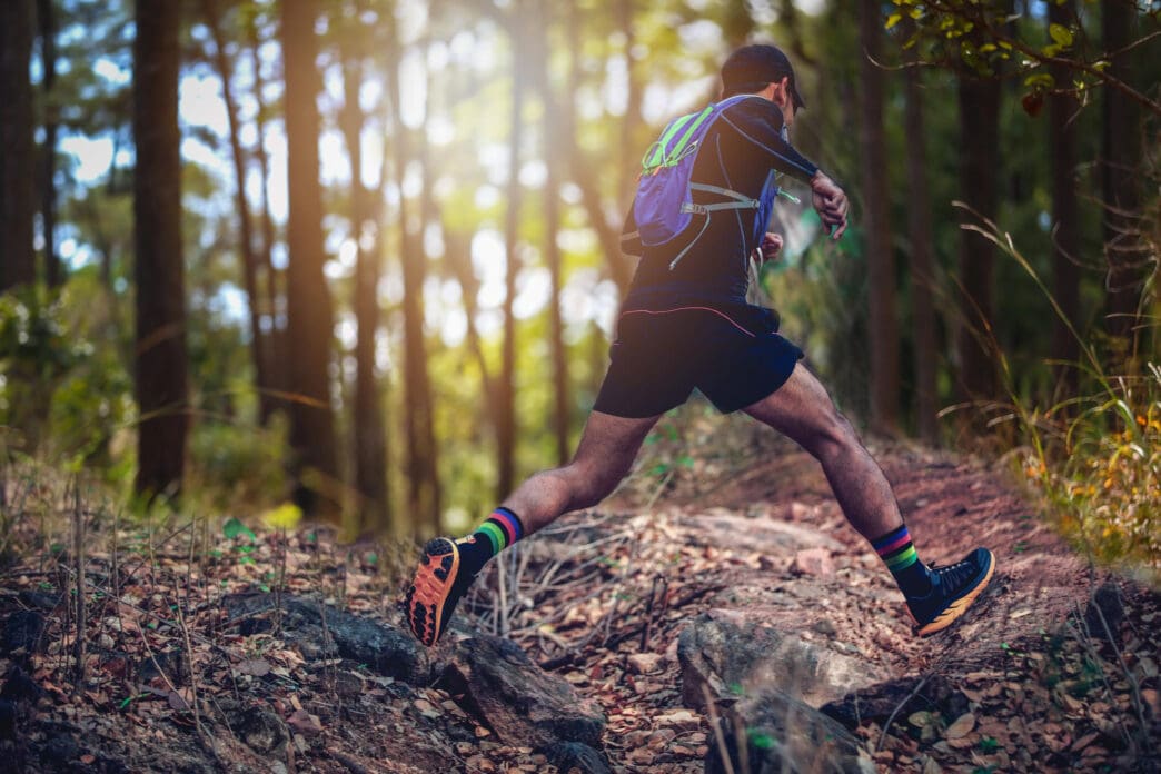 Runner's legs and backpack on a forest trail