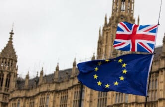 Union Jack and EU flag flying with Parliament building in background