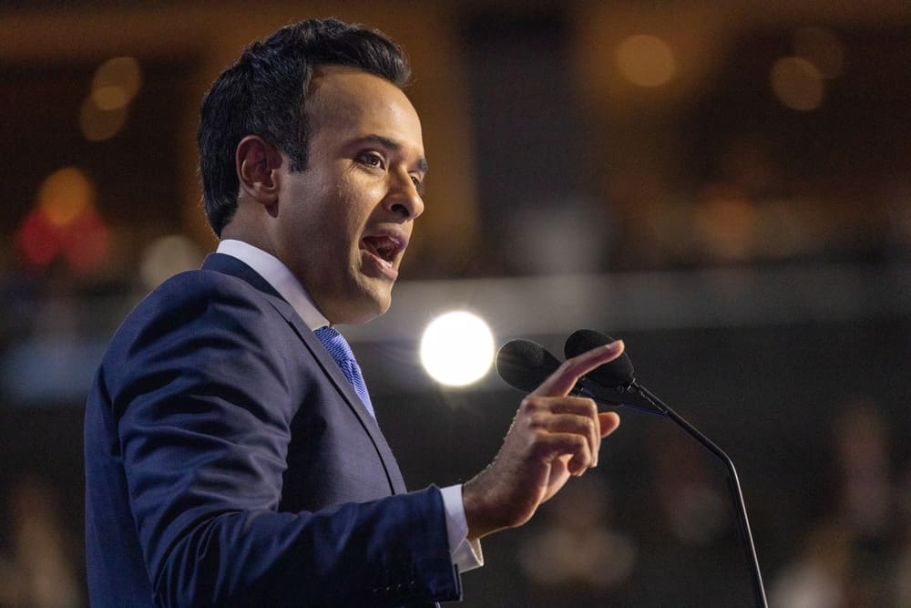 Vivek Ramaswamy, in a suit and tie, speaks passionately into a microphone at a political event