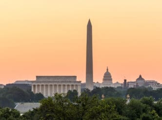 A wide view of the Washington D.C. skyline at sunset, featuring the Lincoln Memorial, Washington Monument, and U.S. Capitol Building