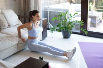 A woman performs a couch dip exercise in a bright, modern living room.