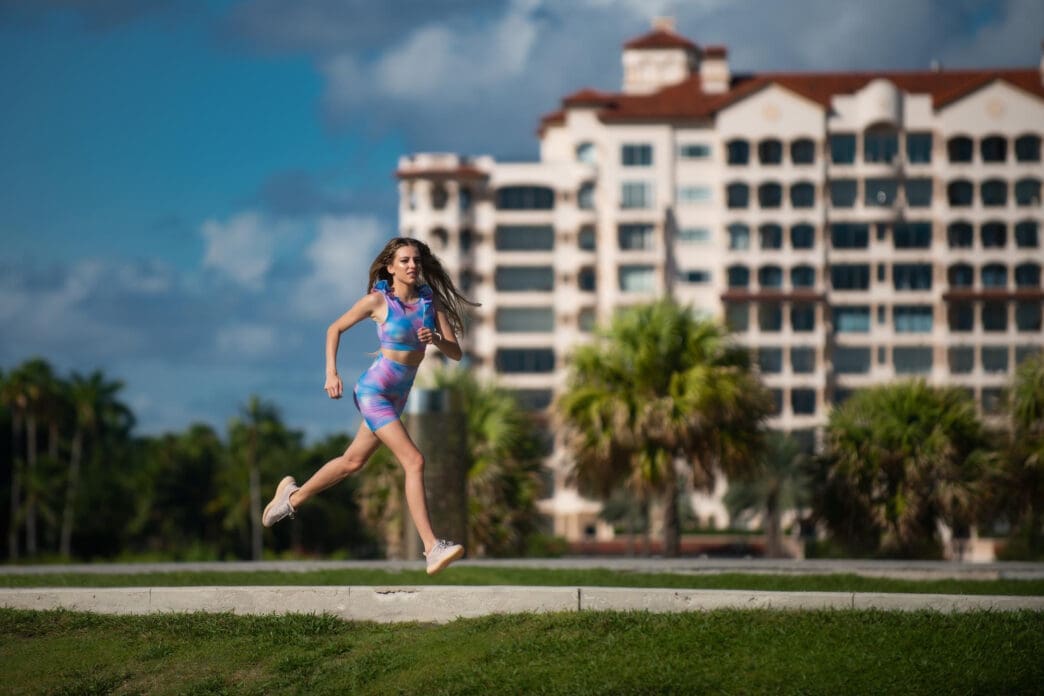 A woman in athletic wear jogs outdoors with a resort-style building in the background.