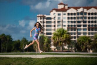 A woman in athletic wear jogs outdoors with a resort-style building in the background.