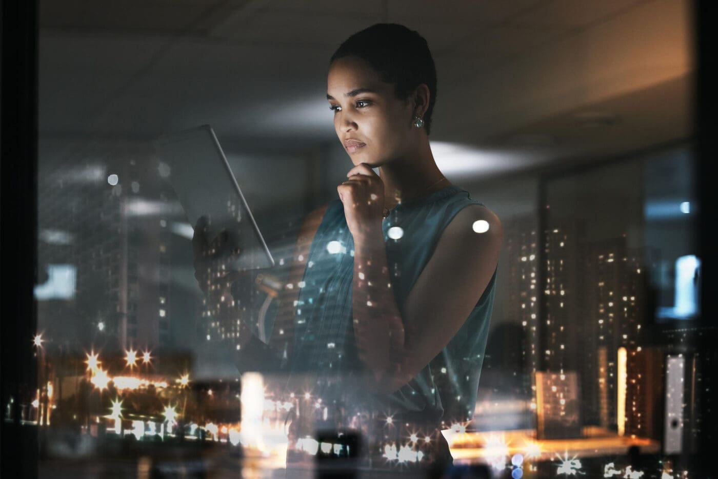 Woman with tablet looking thoughtful with city lights reflection