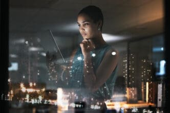 Woman with tablet looking thoughtful with city lights reflection